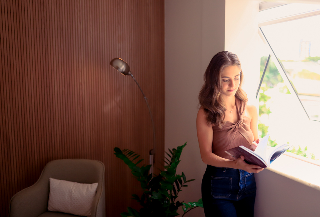 Psicóloga da Perceptiva lendo próxima à janela do consultório